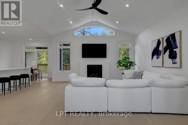 Spacious living area showcasing a fireplace, modern furnishings, and an open layout to the kitchen. - 23 Skeel Court, Ottawa
