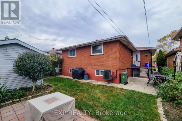 The backyard of the red brick house features a patio, lawn, barbecue, and shed with a fenced perimeter. - 23 Tara Court, Hamilton