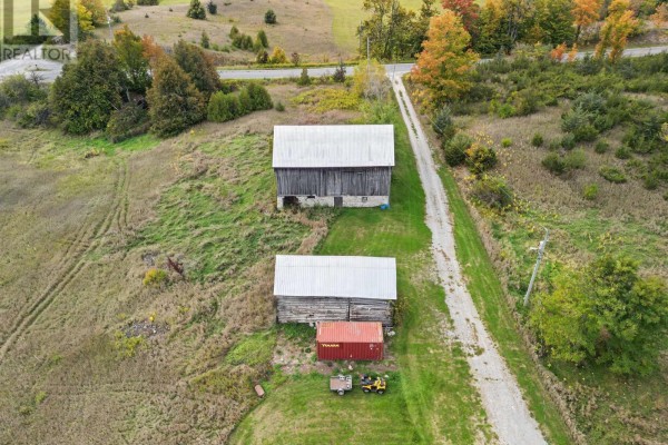 Overhead view of two barns, a shipping container, ATV, and trailer on a grassy field. - 230 Baker Road, Havelock Belmont Methuen