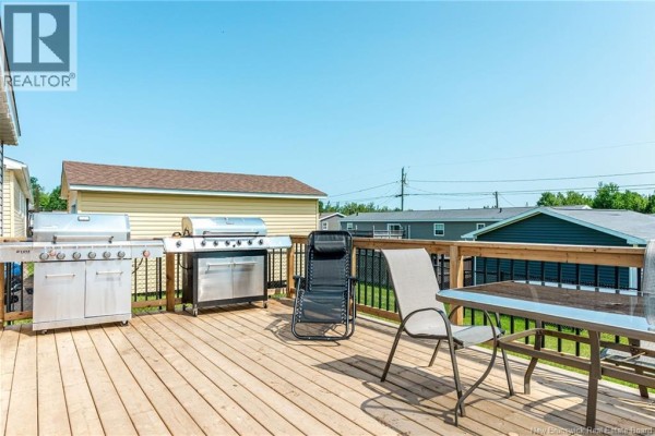Dining area and kitchen with dark cabinets, island, and a window with blinds. - 230 Bonaventure Street, Shediac