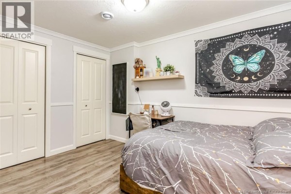 Bedroom with a bed, desk, closet doors, and a wall tapestry featuring a butterfly. - 230 Bonaventure Street, Shediac