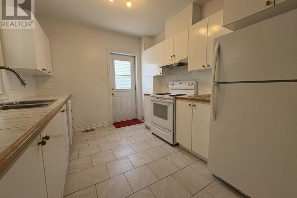 White kitchen with light wood countertops, white appliances, and tile floor. - 230 Cumberland Street, Ottawa