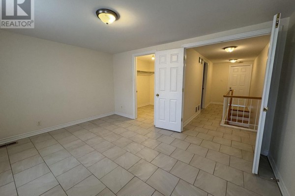 Bedroom with beige walls, tile floor, closet, and hallway view. - 230 Cumberland Street, Ottawa
