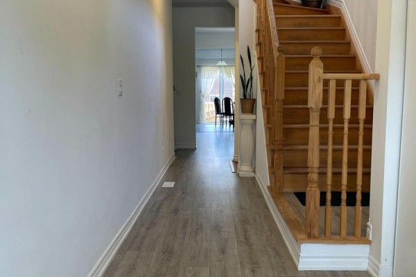 Interior hallway with light wood laminate flooring and a wooden staircase with white risers. - 230 Ridley Crescent, Southgate