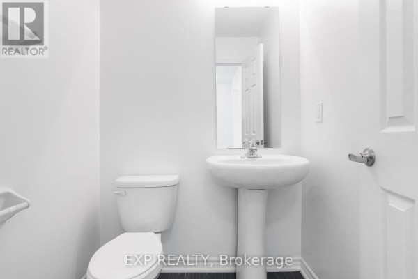 Small powder room with a white pedestal sink, toilet, and dark tiled floor. - 230 Ridley Crescent, Southgate