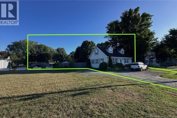 Angle view of a cream colored home with a large tree to the right and bare branches. - 230 Woodstock Road, Fredericton