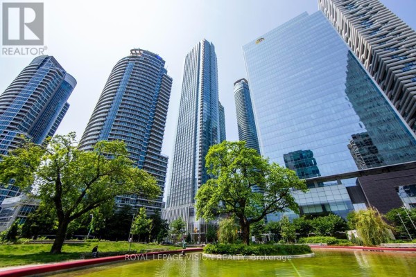 Tall glass skyscrapers surround a treed park with a pond in the foreground. - 2301 - 10 York Street, Toronto