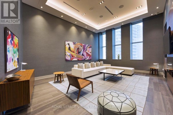 A communal lounge area with a large sectional, art, and modern furniture. - 2301 - 10 York Street, Toronto