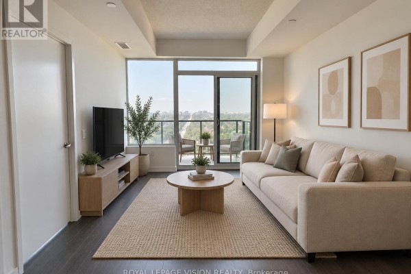 Living room with a beige sofa, coffee table, television, and large windows with a view. - 2301 - 4010 Eglinton Avenue W, Toronto