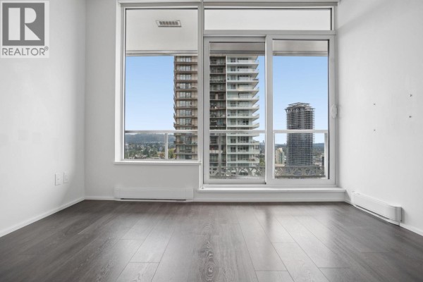 Living area with large windows offering expansive city views and mountain backdrops. - 2301 1955 Alpha Way, Burnaby
