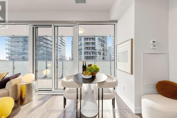Dining area with two chairs and a table next to a sliding glass door overlooking city buildings. - 2302 - 42 Charles Street E, Toronto