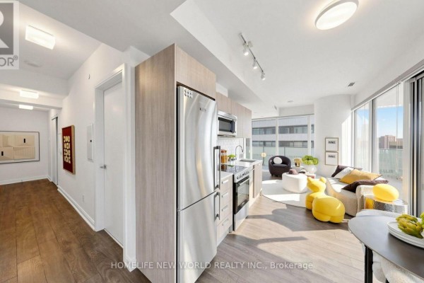Apartment hallway with hardwood floors leading to a modern kitchen and living space. - 2302 - 42 Charles Street E, Toronto