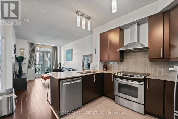 Kitchen with dark wood cabinets, granite countertops, stainless steel appliances, and hardwood floors. - 2304 - 18 Harbour Street, Toronto