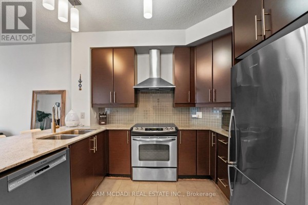 U-shaped kitchen featuring dark wood cabinetry, a stainless steel range, and a granite island. - 2304 - 18 Harbour Street, Toronto