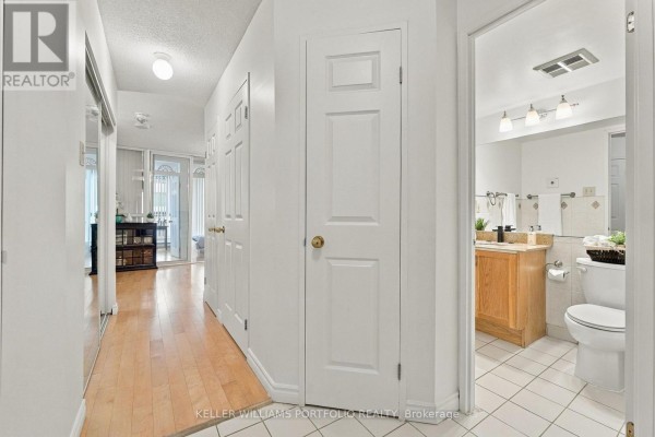 Apartment hallway with light wood floors, white doors, and open bathroom door. - 2304 - 55 Centre Avenue, Toronto