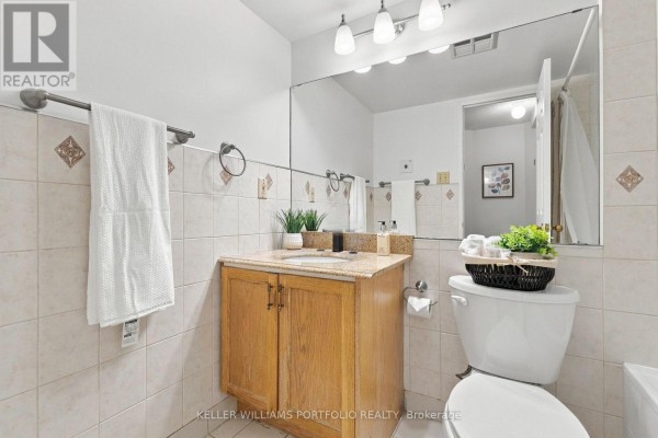 Bathroom vanity with granite countertop, wooden cabinets, and toilet. - 2304 - 55 Centre Avenue, Toronto
