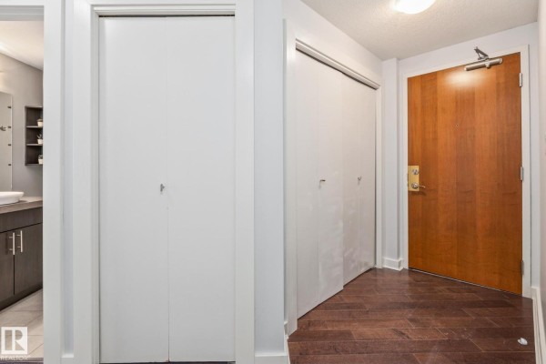 Apartment entrance area with wood door, hardwood floors, and white closet doors. - #2304 10152 104 St Nw, Edmonton