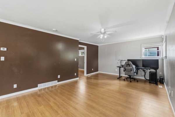 View of the living area showing brown and gray walls, wood floors, and a doorway to another room. - 2304 Mouldstade Road, Abbotsford