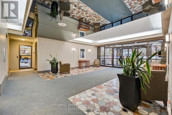 Interior lobby featuring a tiled floor, plants, and seating area with natural light. - #2305 - 1785 Frobisher Lane, Ottawa