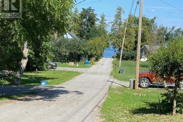 Backyard view of a cottage with a fire pit, chairs, and a kayak. - 2305 Thurstonia Road, Kawartha Lakes