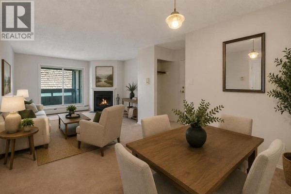 Living and dining area with fireplace, sofa, armchair, and dining table, showing a sliding glass door. - 2306, 315 Southampton Drive Sw, Calgary