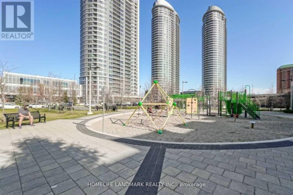 Children's playground with climbing structures and slides in a paved, sandy area. - 2306 - 151 Village Green Square, Toronto