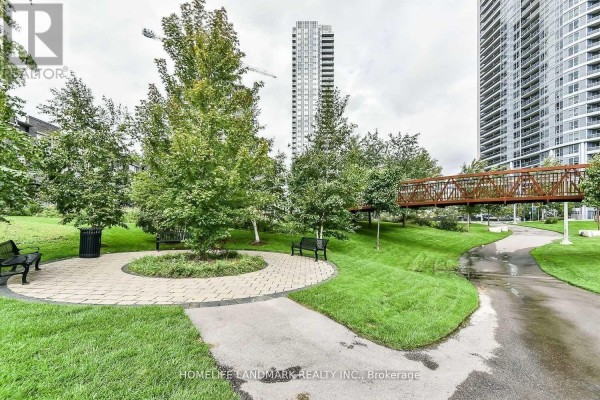 Landscaped park area with walking paths, benches, trees, and a metal footbridge. - 2306 - 151 Village Green Square, Toronto