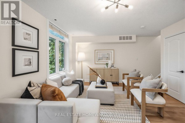 Living room with a white sectional sofa, a patterned rug, and a credenza with artwork. - 2306 - 23 Sudbury Street, Toronto