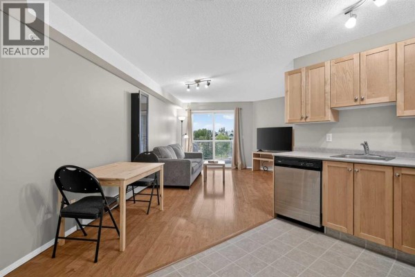 Living area with sofa, coffee table, dining set, and kitchen view. - 2307, 2518 Fish Creek Boulevard Sw, Calgary