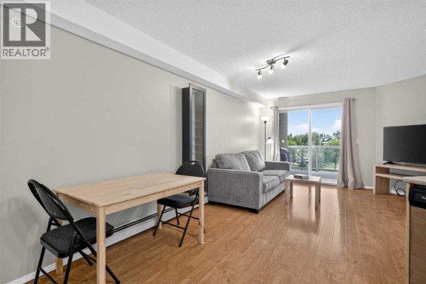 Living room with sofa, dining set, TV stand, and balcony door view. - 2307, 2518 Fish Creek Boulevard Sw, Calgary