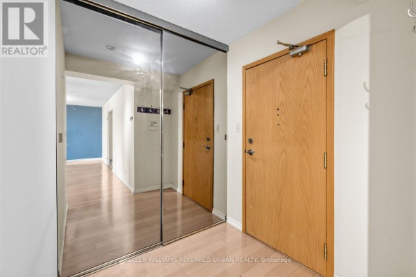 Apartment hallway entrance with a coat rack, security panel, and view into a living area. - 2307 - 215 Wynford Drive, Toronto