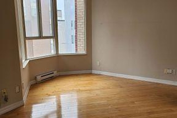 Empty room with hardwood floors and a corner bay window. - 2307 - 55 Centre Avenue, Toronto