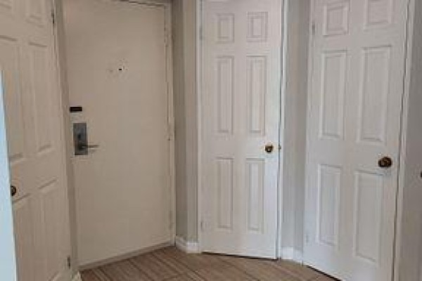 Hallway with multiple white doors and a beige front door. - 2307 - 55 Centre Avenue, Toronto