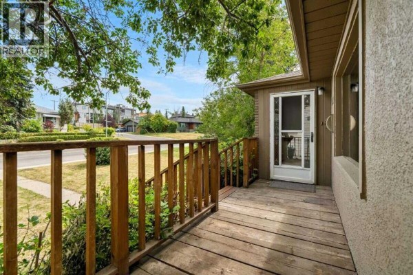 Close-up of the wooden porch and railing on the front of the house, with a glass-paneled door. - 2307 Richmond Road Sw, Calgary