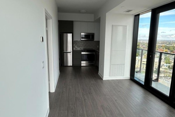 Hallway view towards a large window with a city skyline view and grey wood flooring. - 2308 - 30 Francis Street, Kitchener