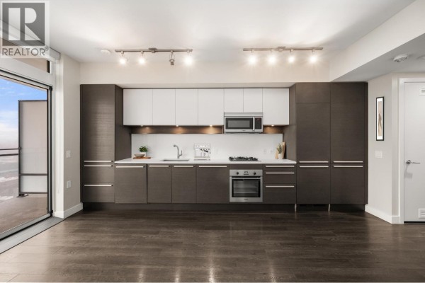 Modern kitchen with dark cabinetry, stainless steel appliances, and white countertops. - 2308 2008 Rosser Avenue, Burnaby