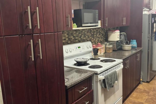 Kitchen with dark wood cabinets, a white stove, and a microwave. - 2309 - 390 Dixon Road, Toronto