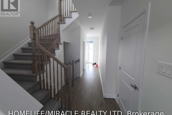 Hallway with dark wood floors, a carpeted staircase, and white doors. - 231 Clonrush Way, Ottawa