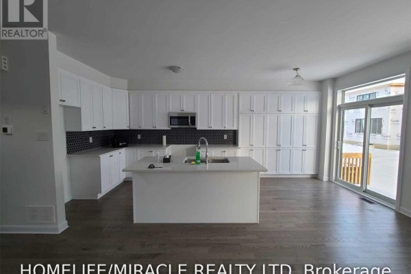 Kitchen with white cabinets, a large island, dark backsplash, and dark wood floors. - 231 Clonrush Way, Ottawa