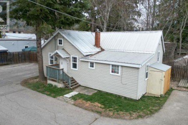 Interior room with light beige walls, a window, and a wooden floor with a baseboard heater. - 231 Finlayson Street, Sicamous