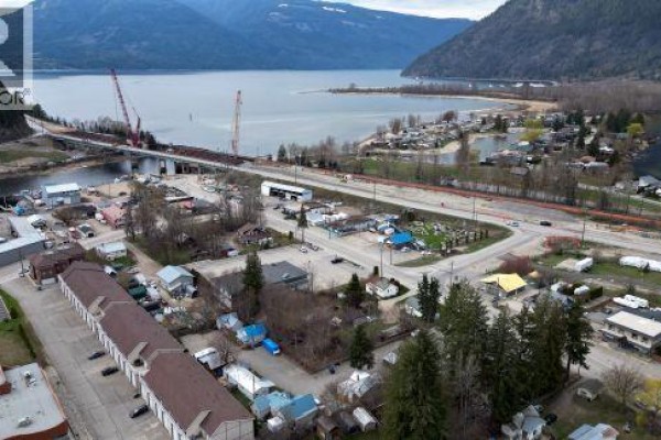 Outdoor paved parking area enclosed by a tall wooden privacy fence with trees in the background. - 231 Finlayson Street, Sicamous