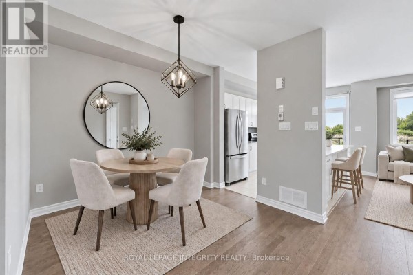 Dining area and kitchen view with a wood table, chairs, light grey walls, and stainless steel appliances. - 231 Mountain Sorrel Way, Ottawa