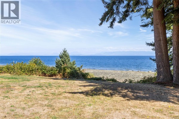 View of the ocean and distant mountains from the property's lawn. - 2310 Seabank Rd, Courtenay
