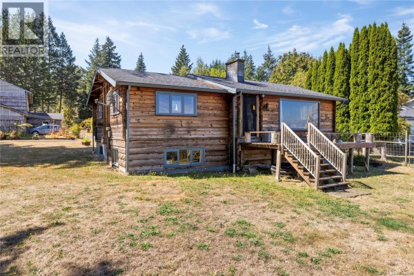 Side view of the wooden house with a deck and stairs. - 2310 Seabank Rd, Courtenay