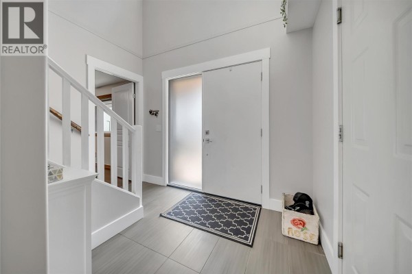 Foyer with light gray walls, tiled floor, white trim, and a double front door. - 2310 Shannon Heights Place, West Kelowna