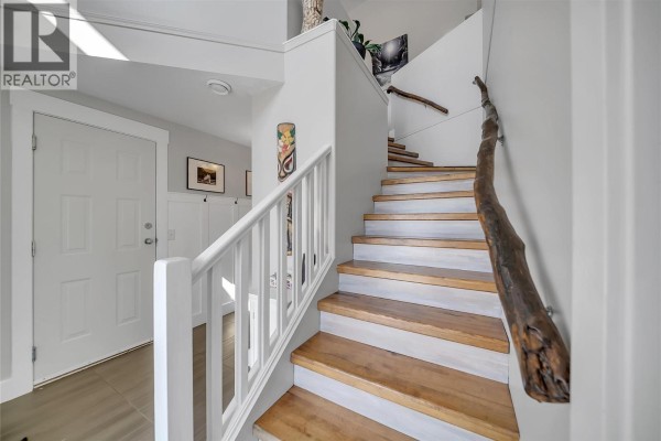Interior staircase with light wood treads, white risers, white railing, and a live-edge wood handrail. - 2310 Shannon Heights Place, West Kelowna