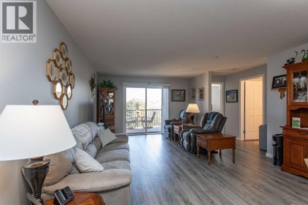 Apartment living room with sofa, chairs, and view of balcony and outdoors. - 2311, 12b Ironside Street, Red Deer