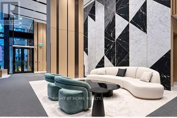 Lobby seating area with a curved white sofa, teal chairs, and a black coffee table. - 2311 - 38 Widmer Street, Toronto