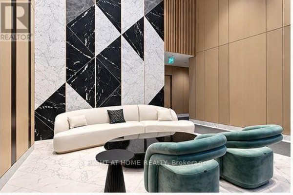 Lobby lounge area with a white sofa, teal chairs, black side tables, and geometric marble wall. - 2311 - 38 Widmer Street, Toronto