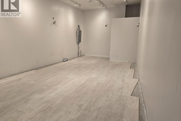 Empty commercial interior with white walls, laminate flooring, and electrical panel. - 2311 4500 Kingsway, Burnaby